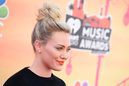 Hilary Duff con un moño alto y labios naranjas