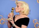 Lady Gaga con un peinado clásico besando su Globo de Oro